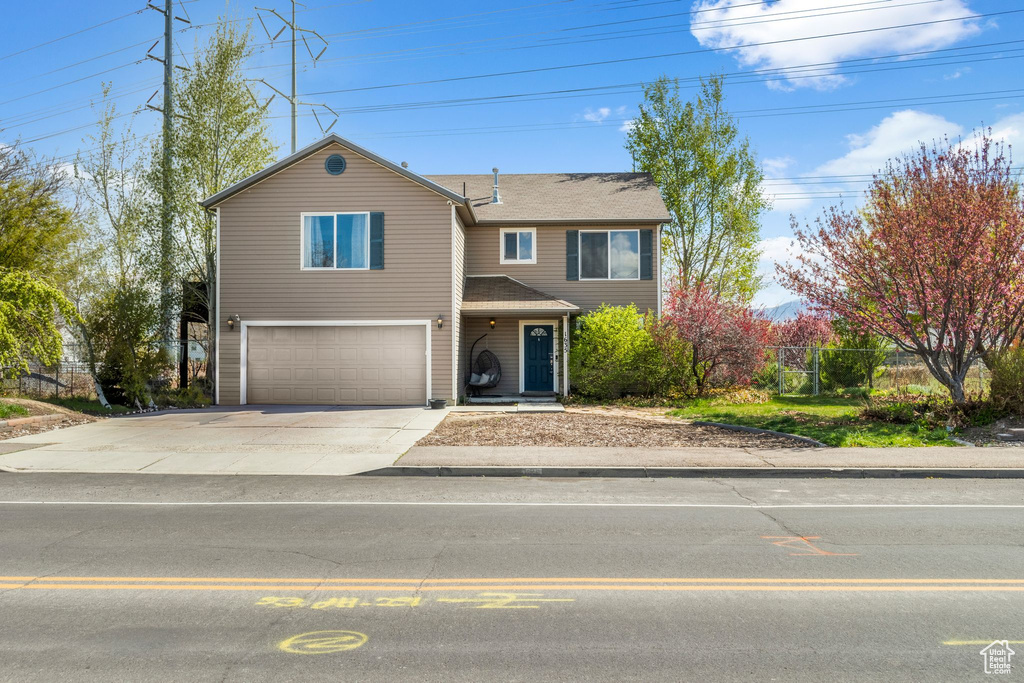 Traditional-style home featuring fence, driveway, and a garage