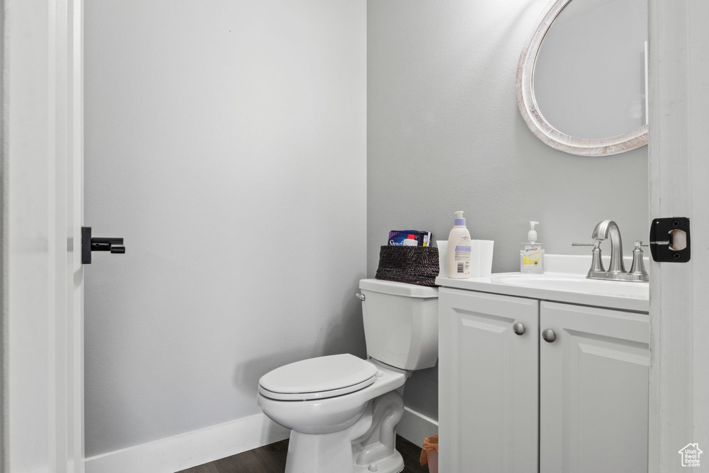 Bathroom with baseboards, wood finished floors, toilet, and vanity