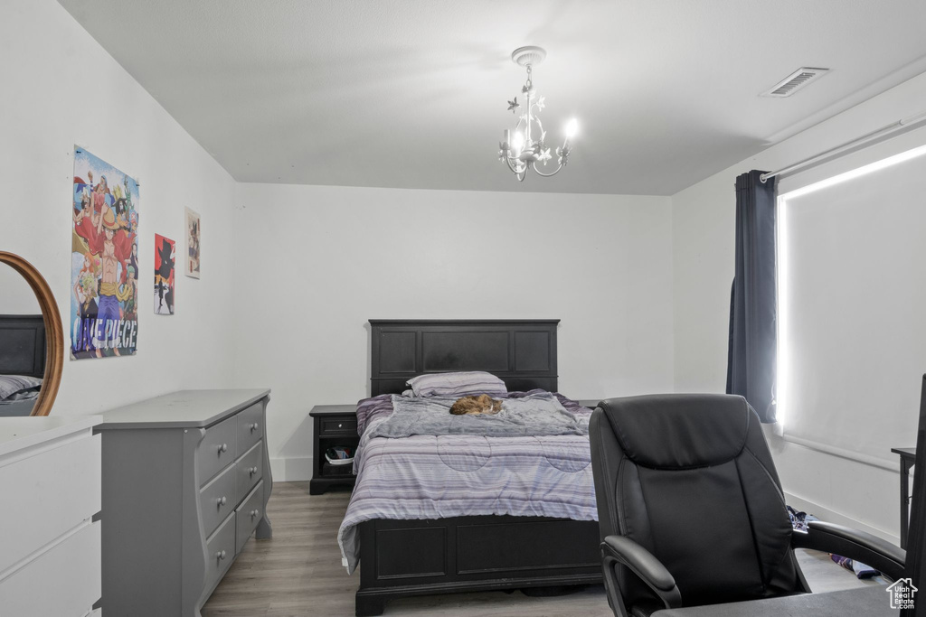 Bedroom with light wood finished floors, a notable chandelier, and visible vents