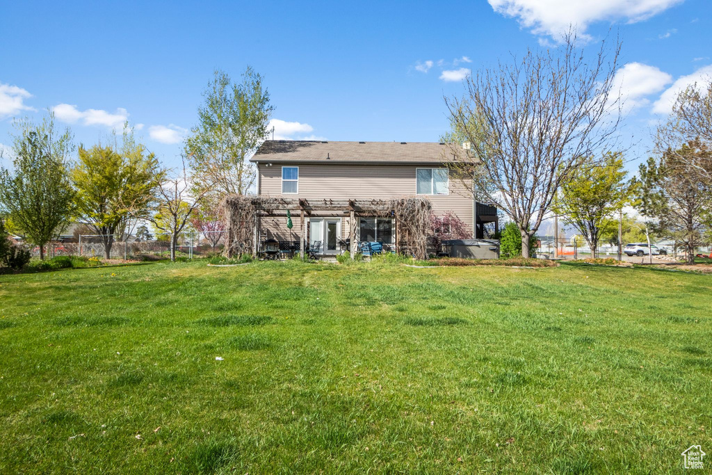 Back of property featuring fence, a yard, and a pergola