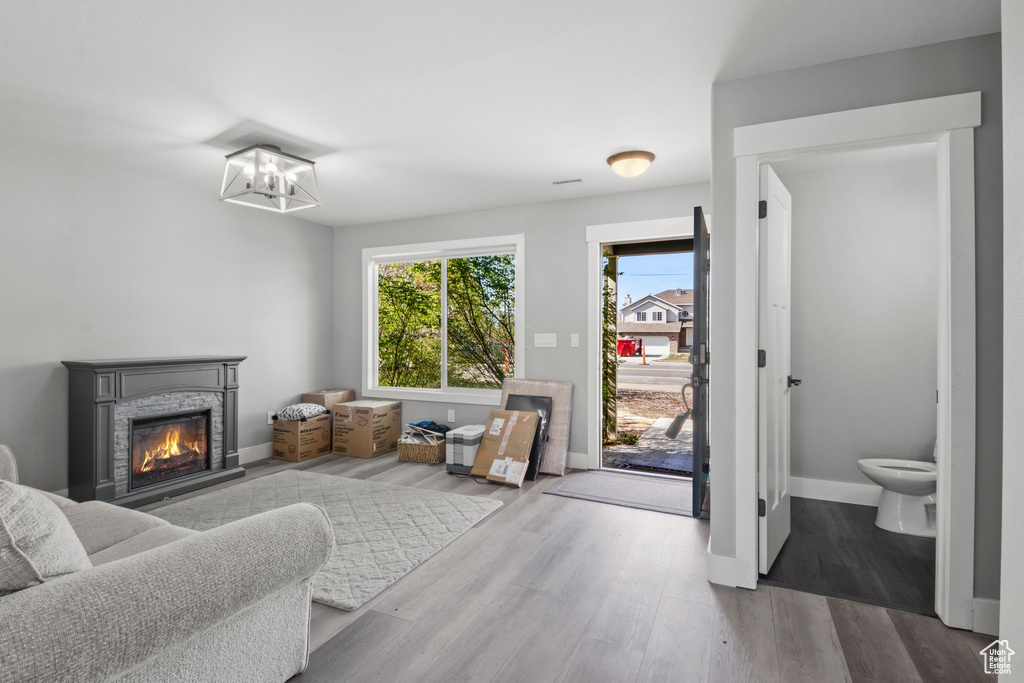 Living room with a chandelier, baseboards, wood finished floors, and a fireplace