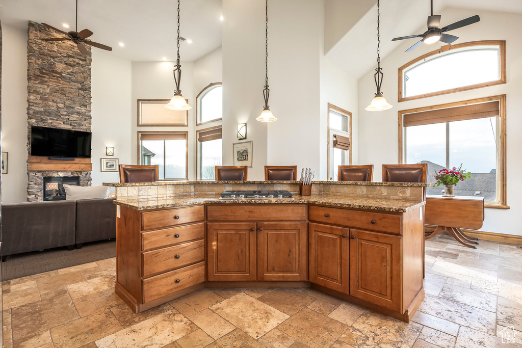 Kitchen featuring stone tile floors, ceiling fan, and high vaulted ceiling