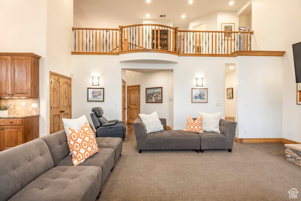Living room with carpet floors, recessed lighting, and a towering ceiling