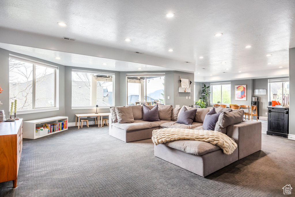 Carpeted living room with recessed lighting, baseboards, and visible vents