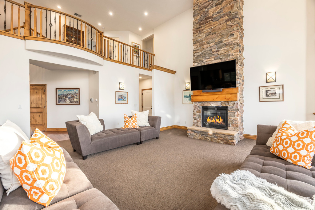 Living room with a high ceiling, a stone fireplace, carpet, recessed lighting, and baseboards