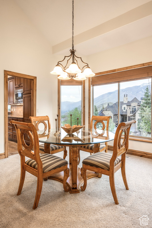 Dining area with an inviting chandelier, a mountain view, baseboards, and light colored carpet