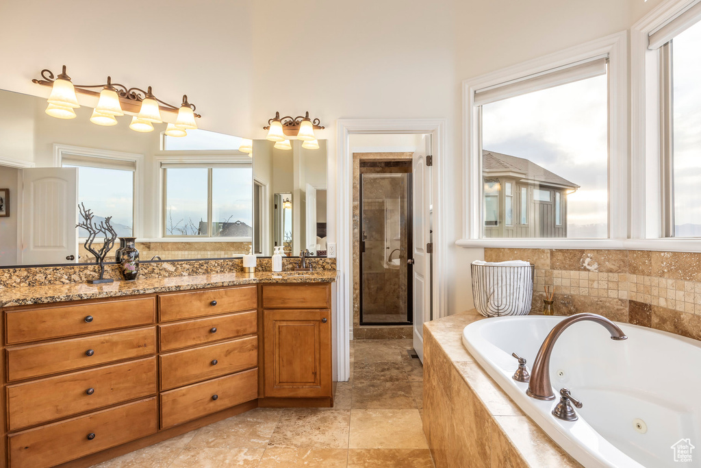 Full bath with a jetted tub, vanity, a healthy amount of sunlight, and a shower stall