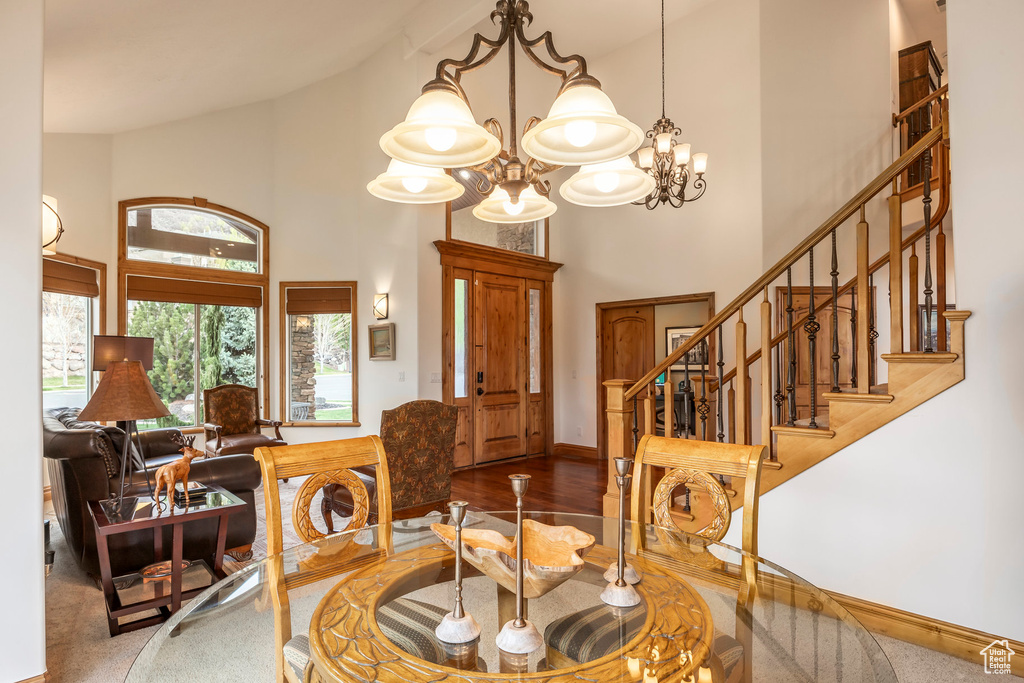 Dining area featuring an inviting chandelier, high vaulted ceiling, baseboards, and stairway