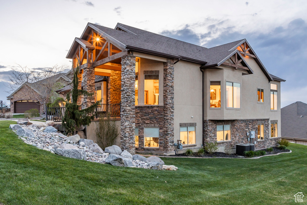 View of property exterior with a lawn, stucco siding, and stone siding