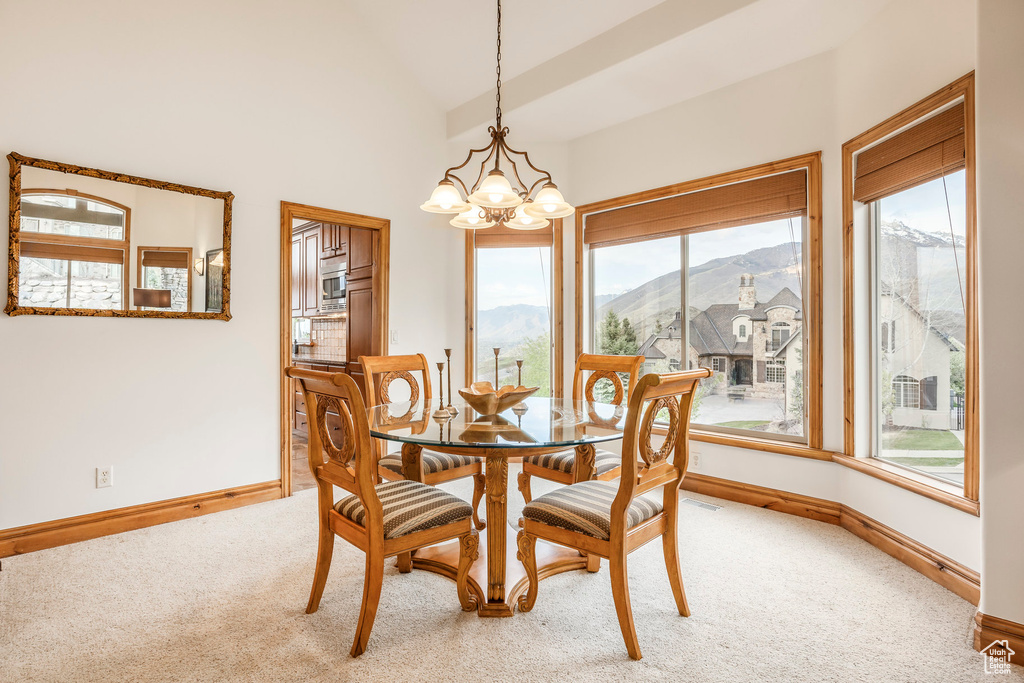Carpeted dining area featuring baseboards, plenty of natural light, and a chandelier