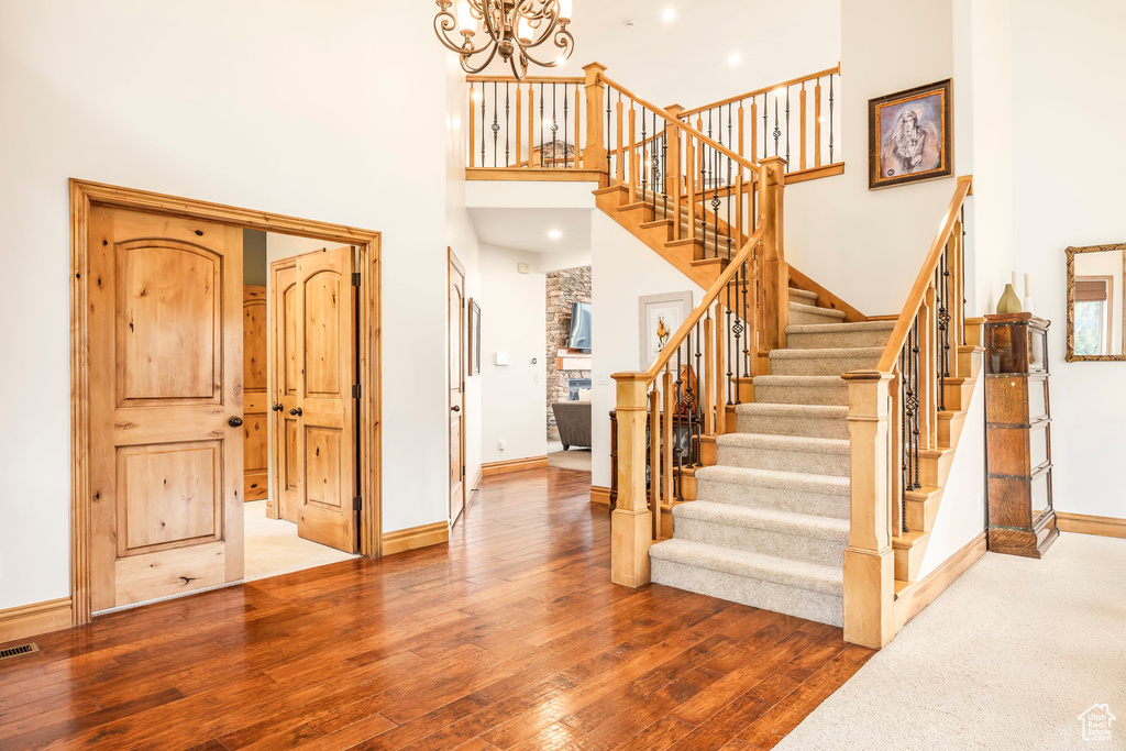Stairs featuring a high ceiling, a chandelier, baseboards, and hardwood / wood-style floors