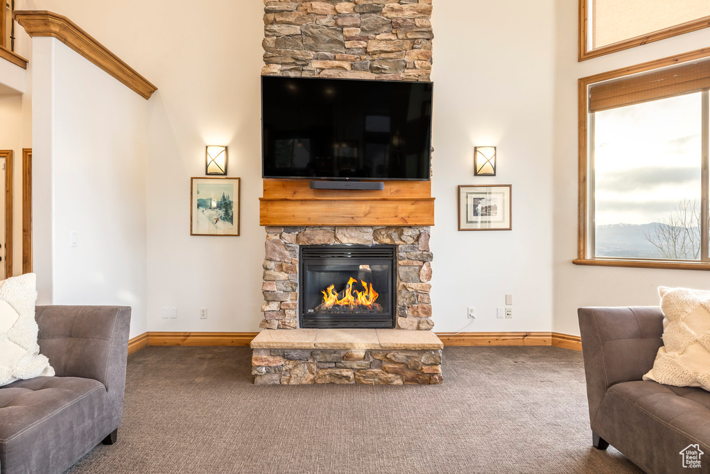 Carpeted living area with baseboards and a stone fireplace