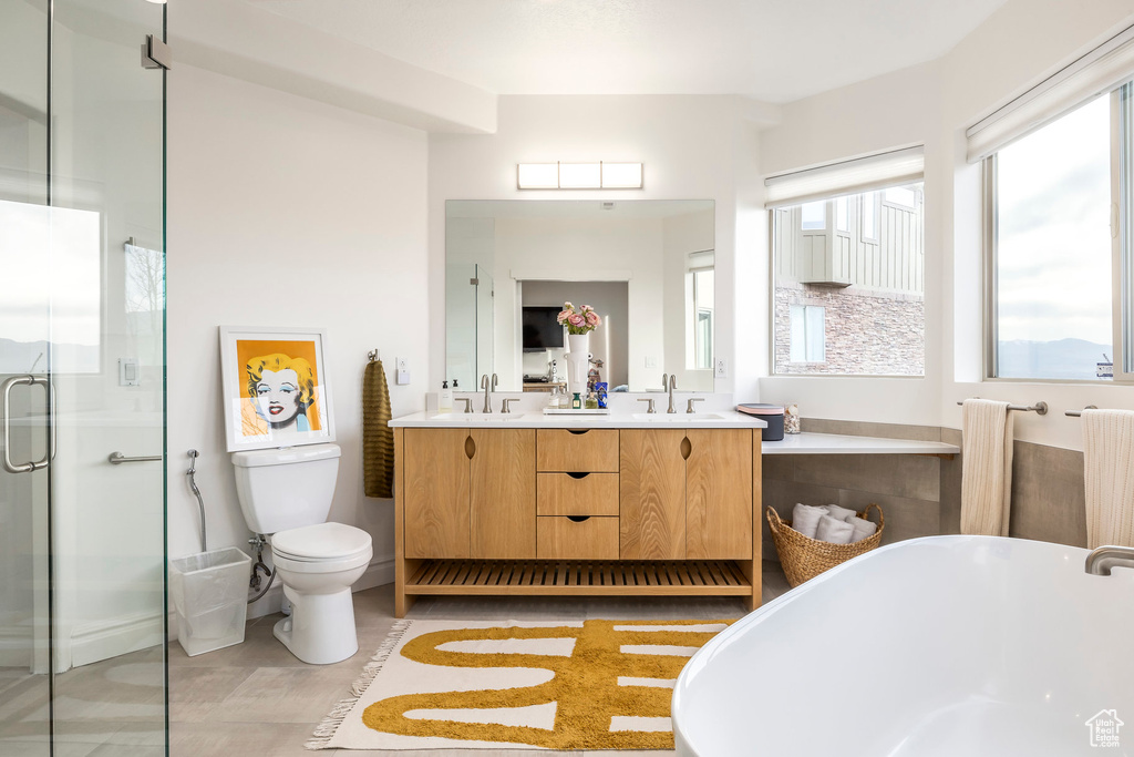 Full bathroom featuring a sink, double vanity, toilet, a freestanding tub, and a shower stall