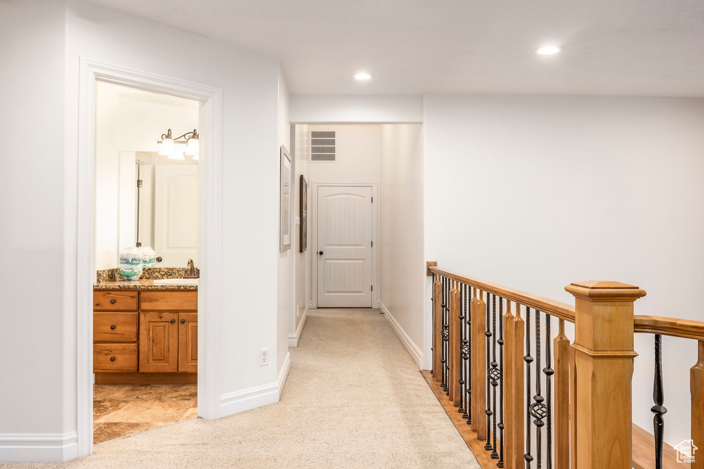Corridor with recessed lighting, a sink, visible vents, and light carpet