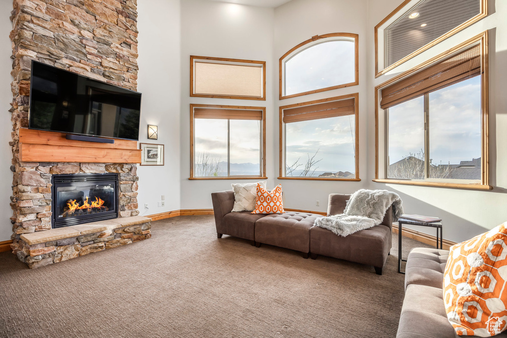 Living room with baseboards, carpet, a high ceiling, and a fireplace