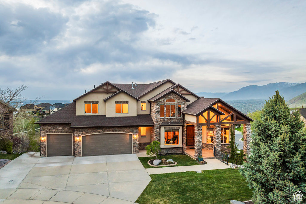 Craftsman-style house with stone siding, a garage, stucco siding, a front yard, and driveway