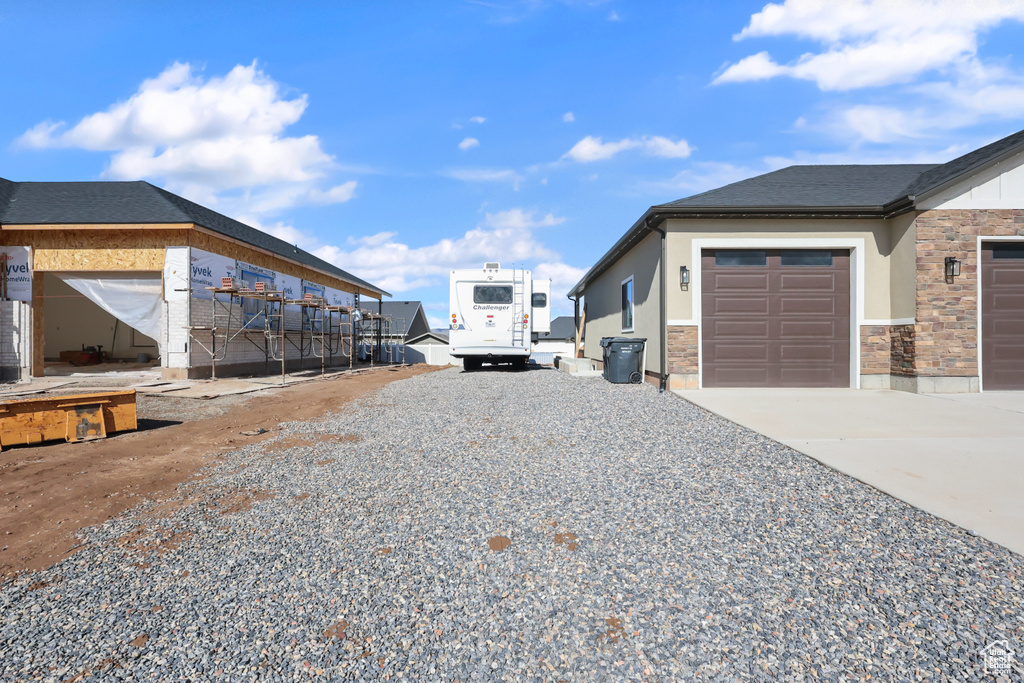 View of home's exterior with stucco siding, driveway, stone siding, and a garage