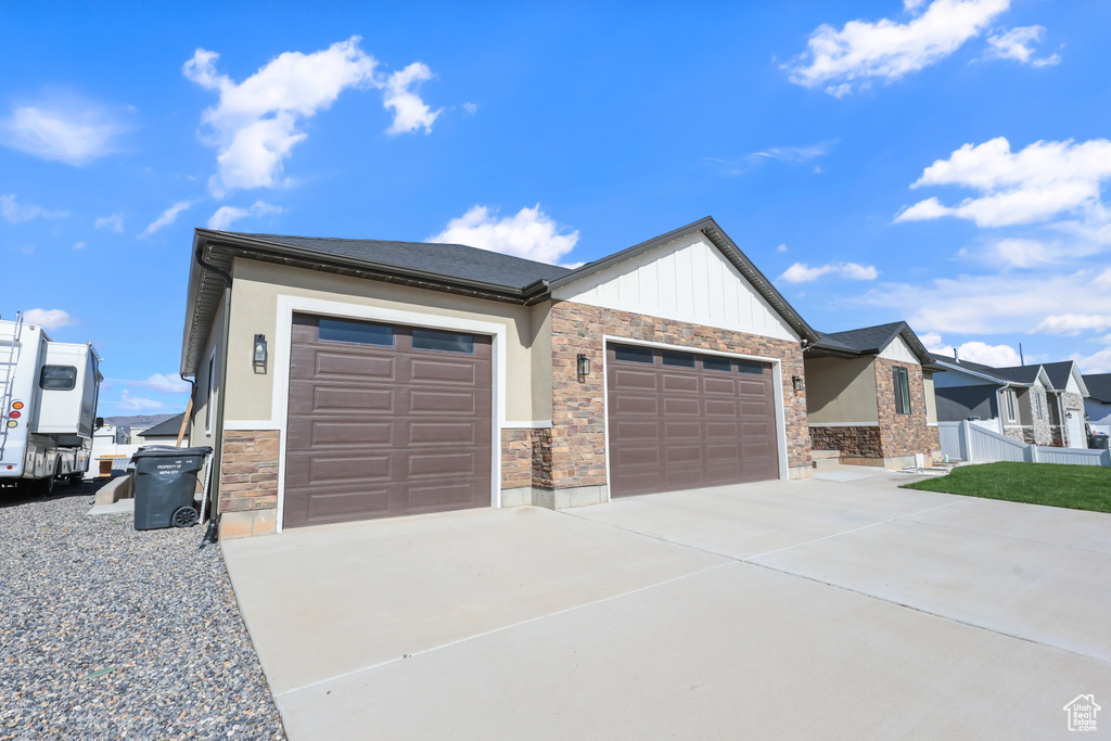 View of front of property with a garage, driveway, and stone siding