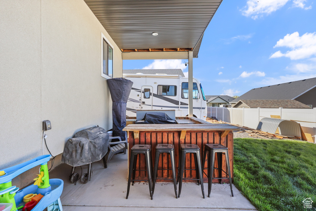 View of patio featuring fence, outdoor dry bar, and a residential view
