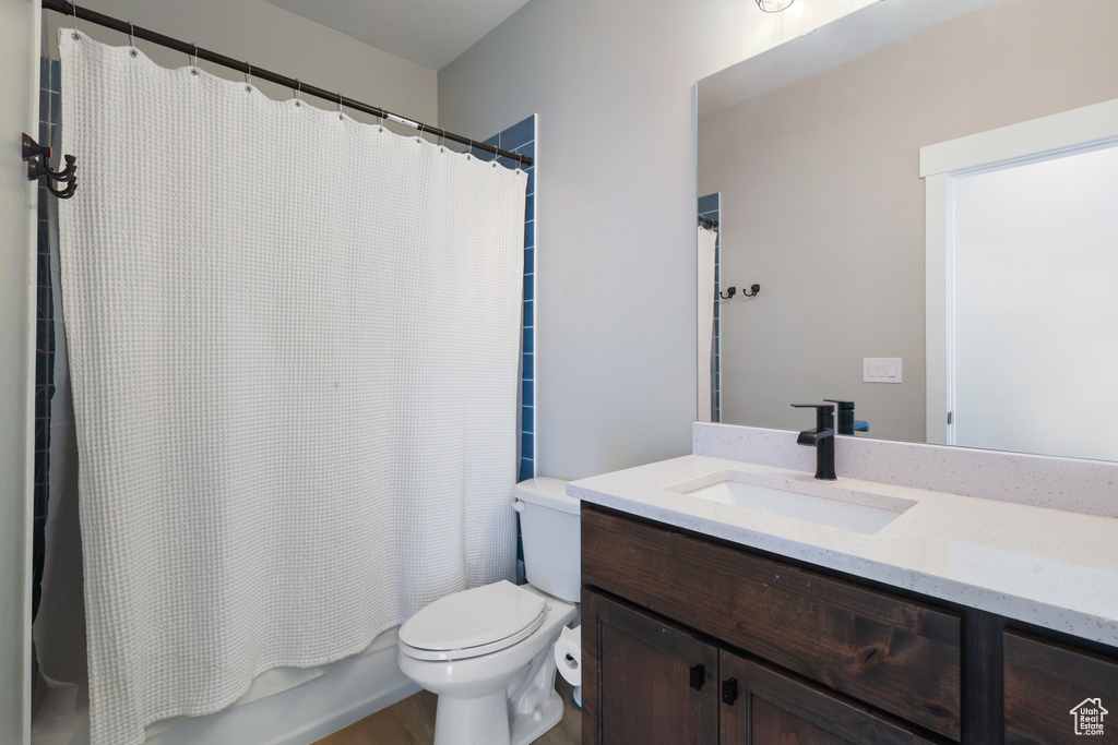 Bathroom featuring vanity, toilet, and shower / tub combo with curtain