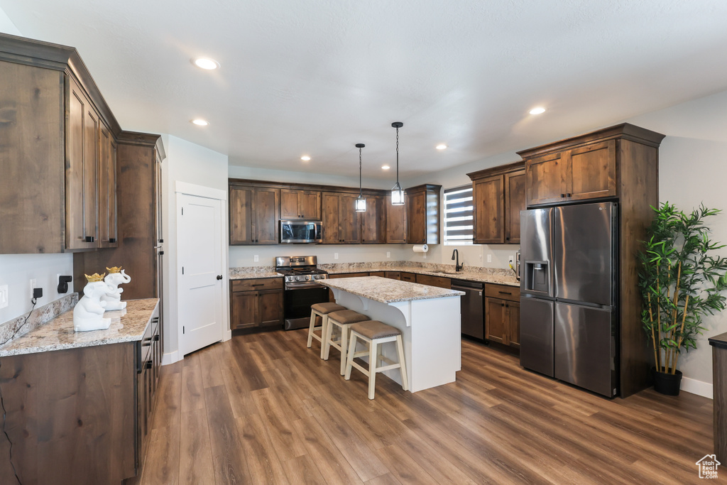Kitchen with stainless steel appliances, dark brown cabinetry, dark wood-style floors, and a sink
