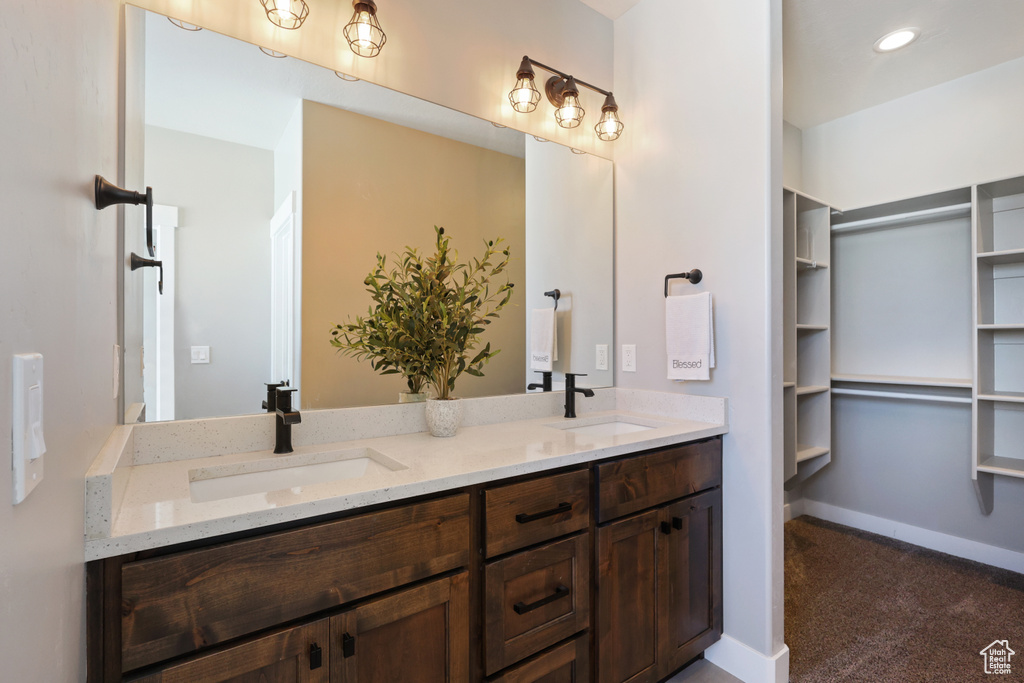 Full bathroom featuring double vanity, baseboards, and a sink