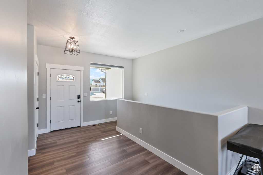 Entryway with baseboards, a notable chandelier, and dark wood-style floors