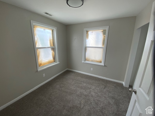 Empty room with baseboards, visible vents, a wealth of natural light, and carpet flooring