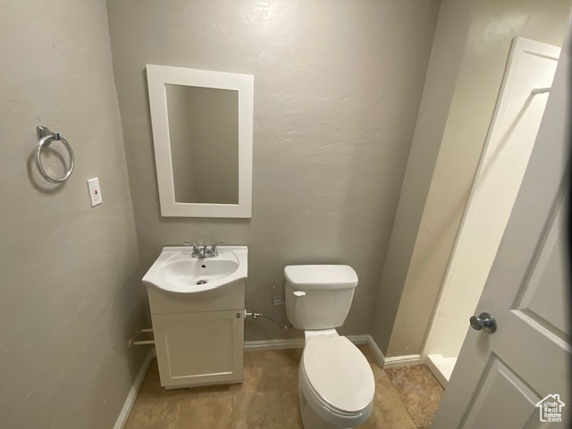 Bathroom featuring toilet, vanity, and baseboards