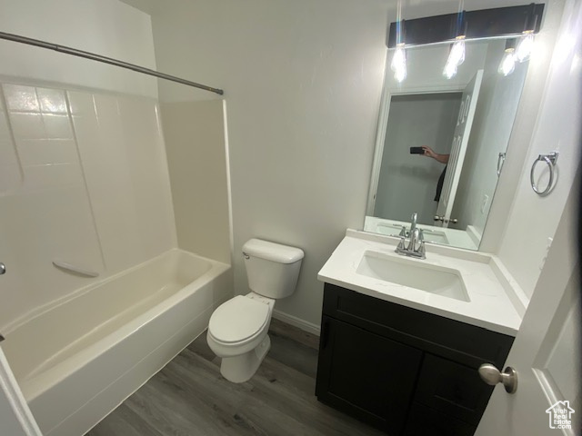 Bathroom with vanity, toilet, baseboards, tub / shower combination, and wood finished floors