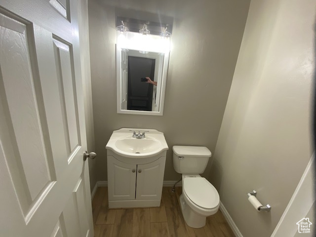 Bathroom with toilet, wood finished floors, vanity, and baseboards