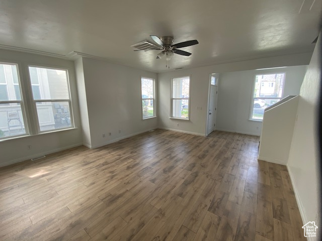 Spare room with crown molding, a ceiling fan, wood finished floors, and baseboards