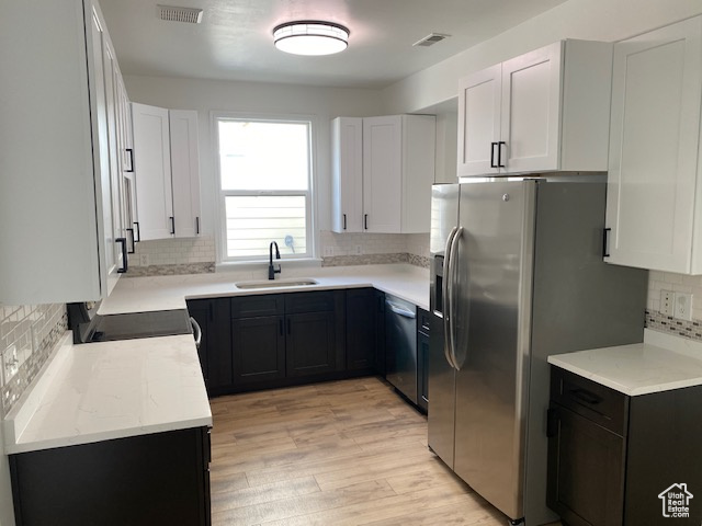 Kitchen featuring light wood-style flooring, decorative backsplash, appliances with stainless steel finishes, a sink, and visible vents
