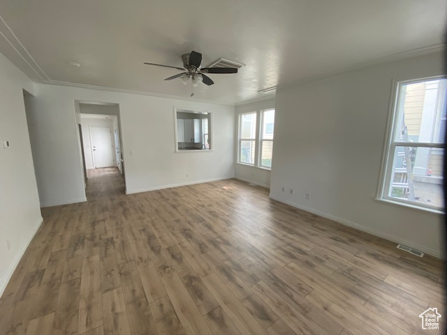 Spare room with crown molding, a ceiling fan, visible vents, and wood finished floors