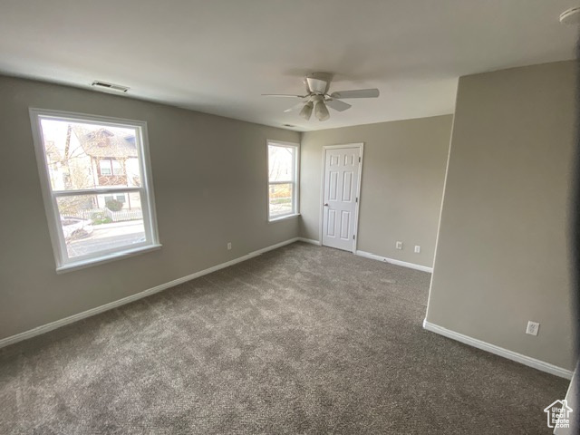 Empty room with visible vents, ceiling fan, carpet, and baseboards