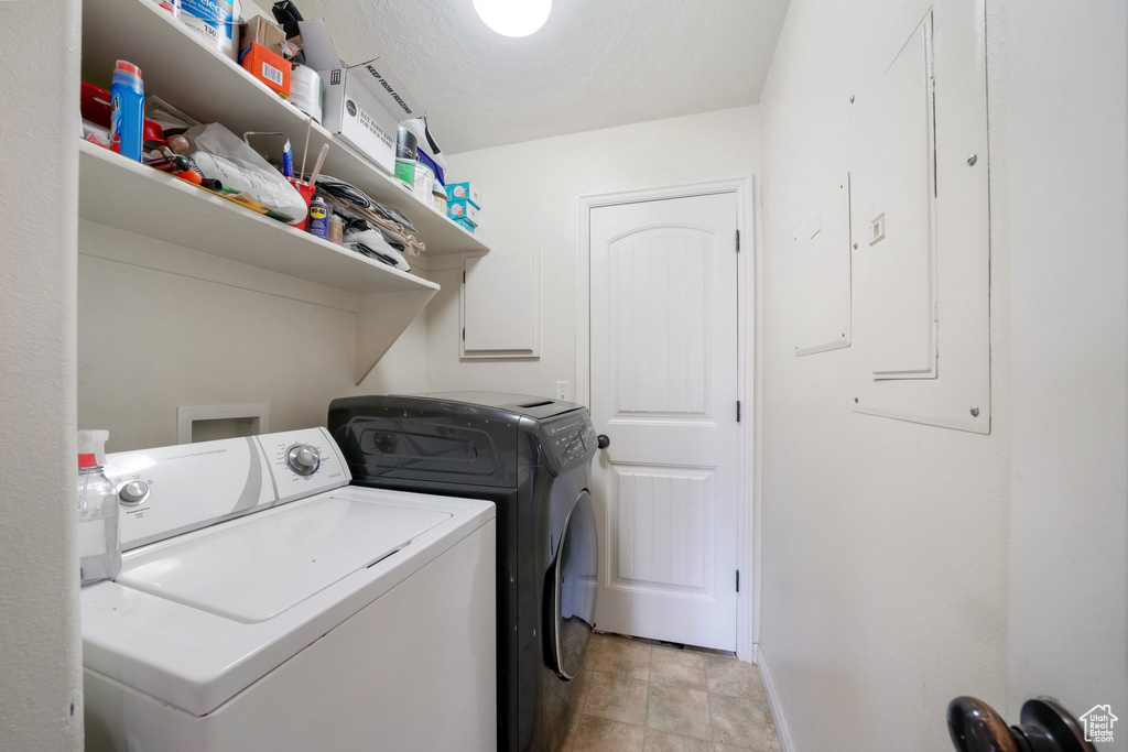 Laundry area with laundry area, baseboards, electric panel, and washer and dryer