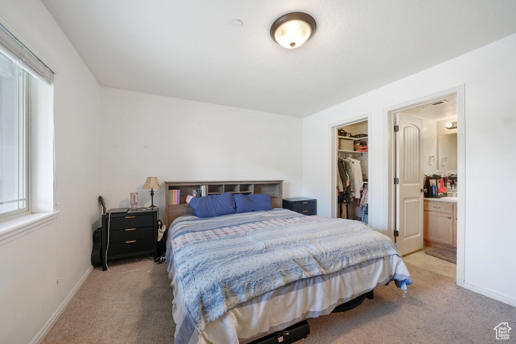 Bedroom featuring baseboards, a spacious closet, light carpet, and a closet