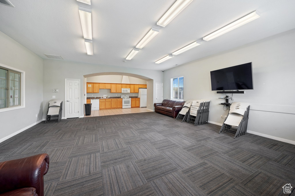 Interior space with dark carpet, arched walkways, baseboards, and visible vents