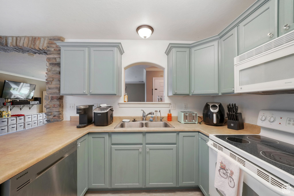 Kitchen with a sink, light countertops, and white appliances