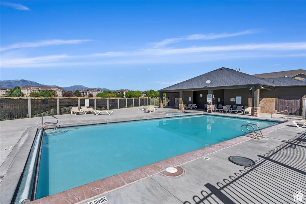 Community pool featuring fence, a mountain view, and a patio