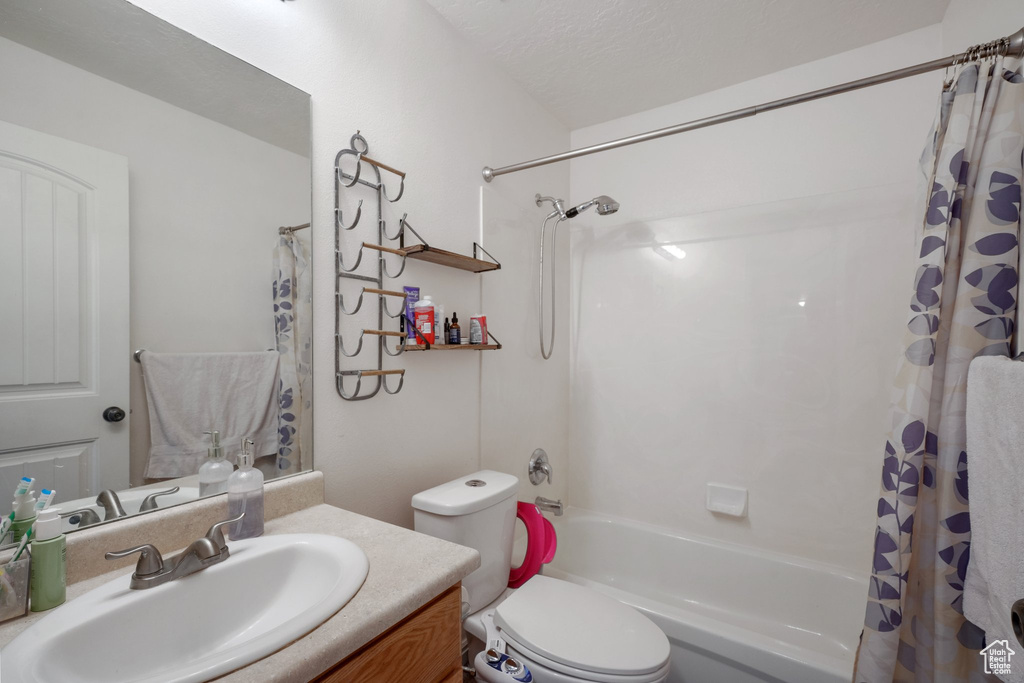 Bathroom with vanity, toilet, and shower / tub combo with curtain