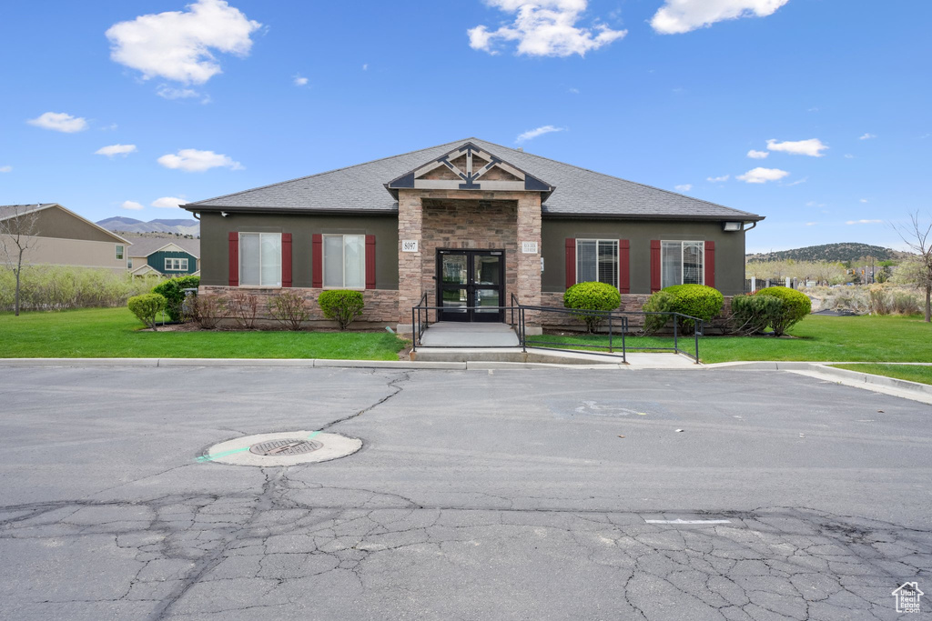 View of front of property with a front lawn, uncovered parking, and stone siding