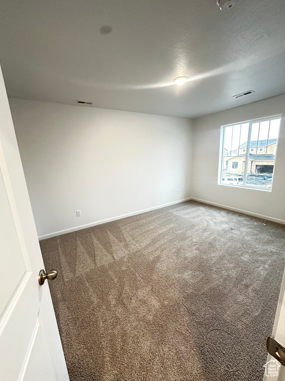 Carpeted empty room with baseboards and a textured ceiling