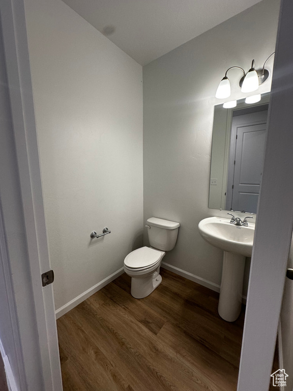 Bathroom featuring wood finished floors, toilet, and baseboards