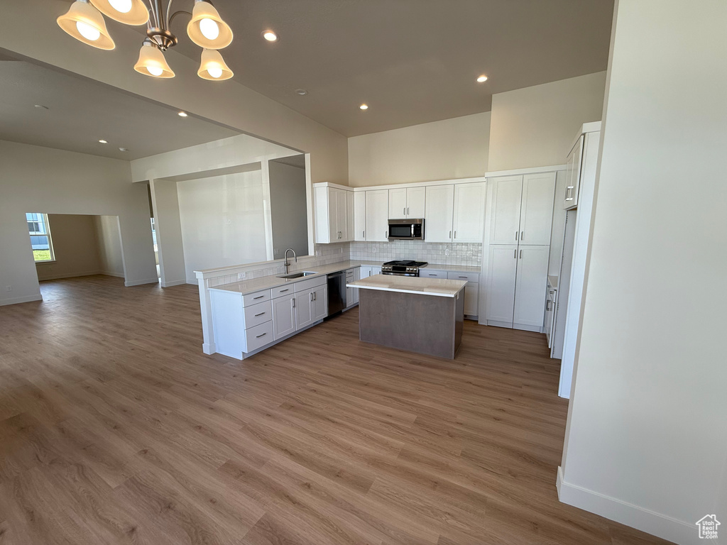Kitchen featuring decorative backsplash, a center island, a sink, open floor plan, and stainless steel appliances