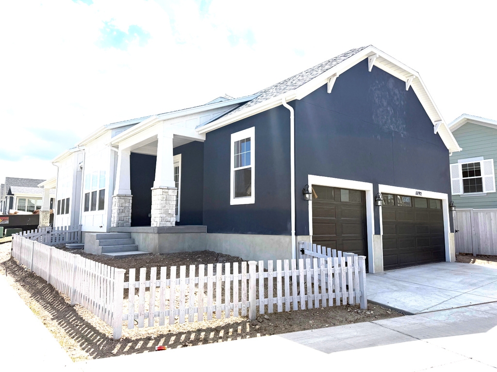 View of front of property with fence, an attached garage, stucco siding, concrete driveway, and covered porch