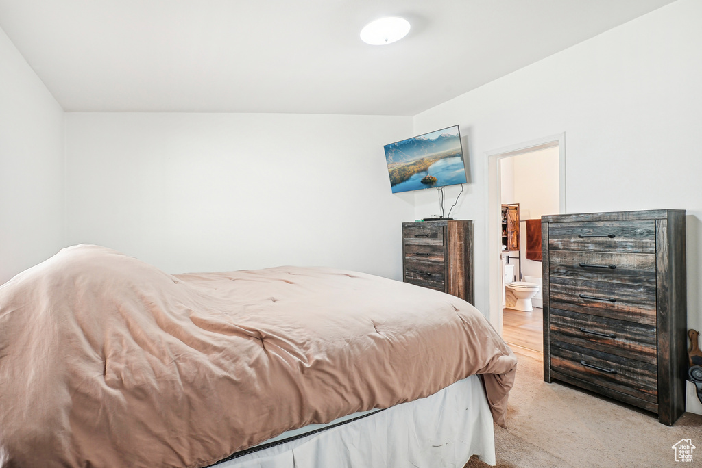 Bedroom with beverage cooler, ensuite bath, and light colored carpet