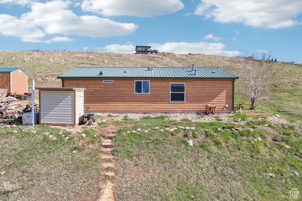 Rear view of house featuring a storage unit and metal roof