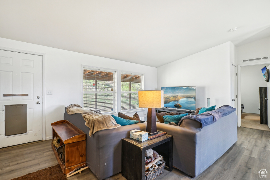 Living room with vaulted ceiling, wood finished floors, and visible vents