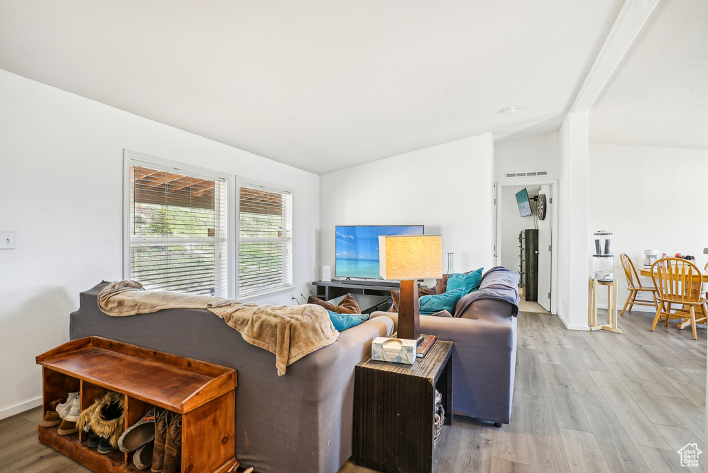 Living room featuring baseboards, vaulted ceiling, wood finished floors, and visible vents